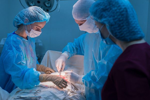 Children's surgeons perform urological surgery. A man and a woman in a mask, and a blue sterile gown, in the operating room.